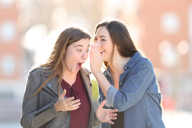 Gossip woman telling secret to her surprised friend